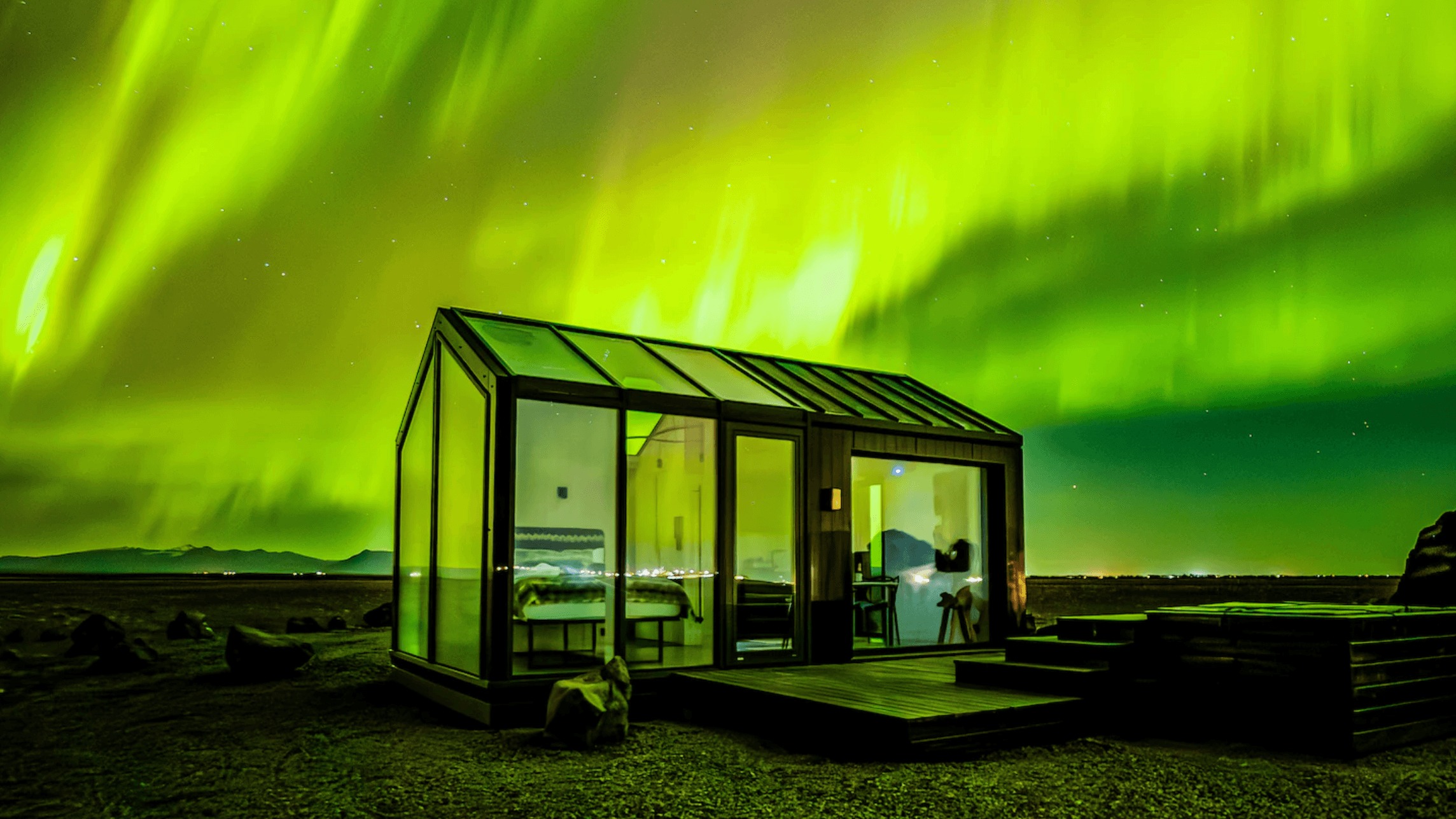 Kuzey ışıkları altında sıcak pencere ışıkları yayan geleneksel İskandinav evi